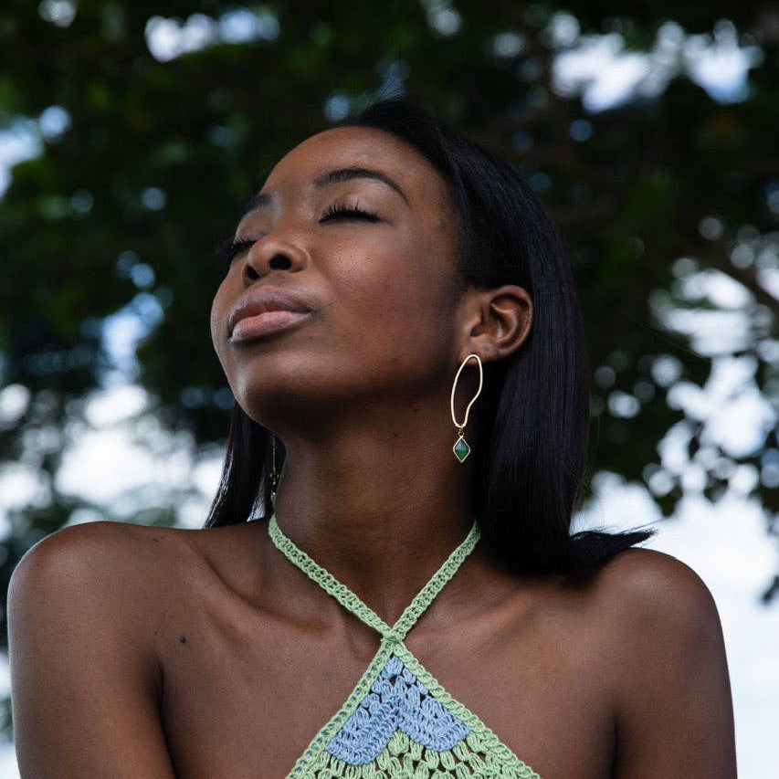 Woman wearing a colorful crochet top with a blurred natural background