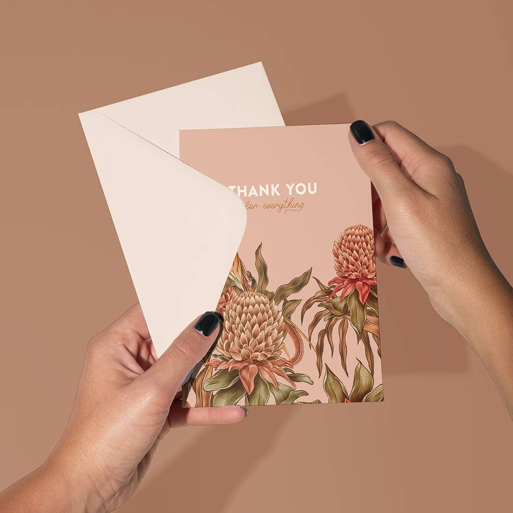 Floral card with 'Thank You' text held by hands against a brown background