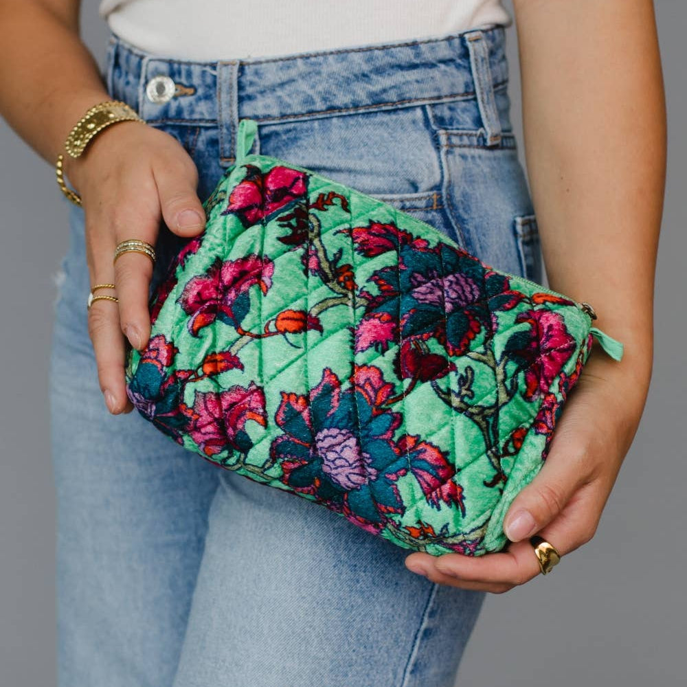 Person holding a floral-patterned clutch bag against a neutral background