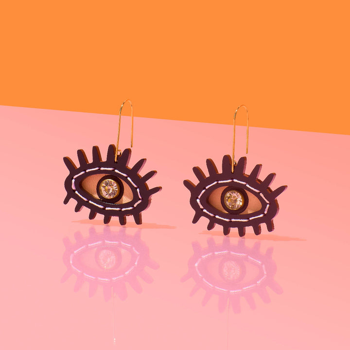 Earring with eye design on a pink and orange background