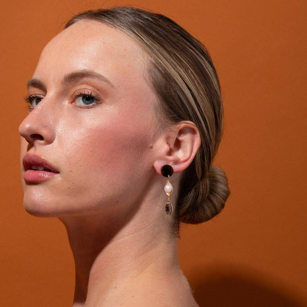 Woman wearing earrings against an orange background