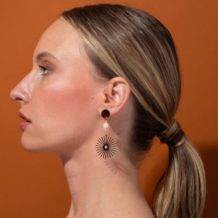 Woman wearing earrings with a brown background
