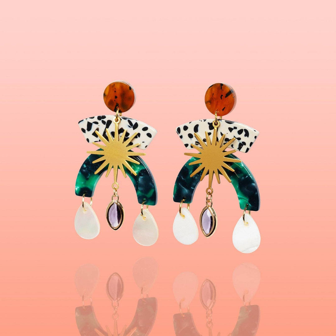 Pair of colorful earrings with a star design on a pink background