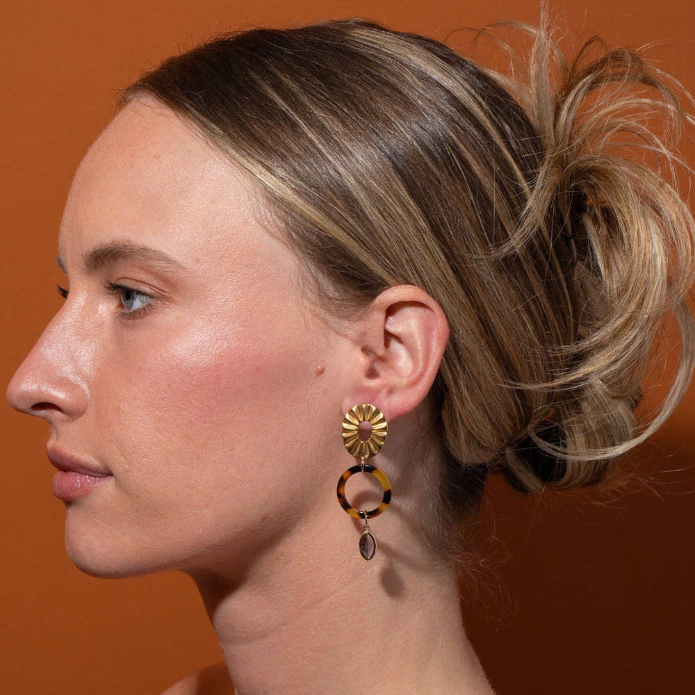 Woman wearing a pair of earrings against an orange background