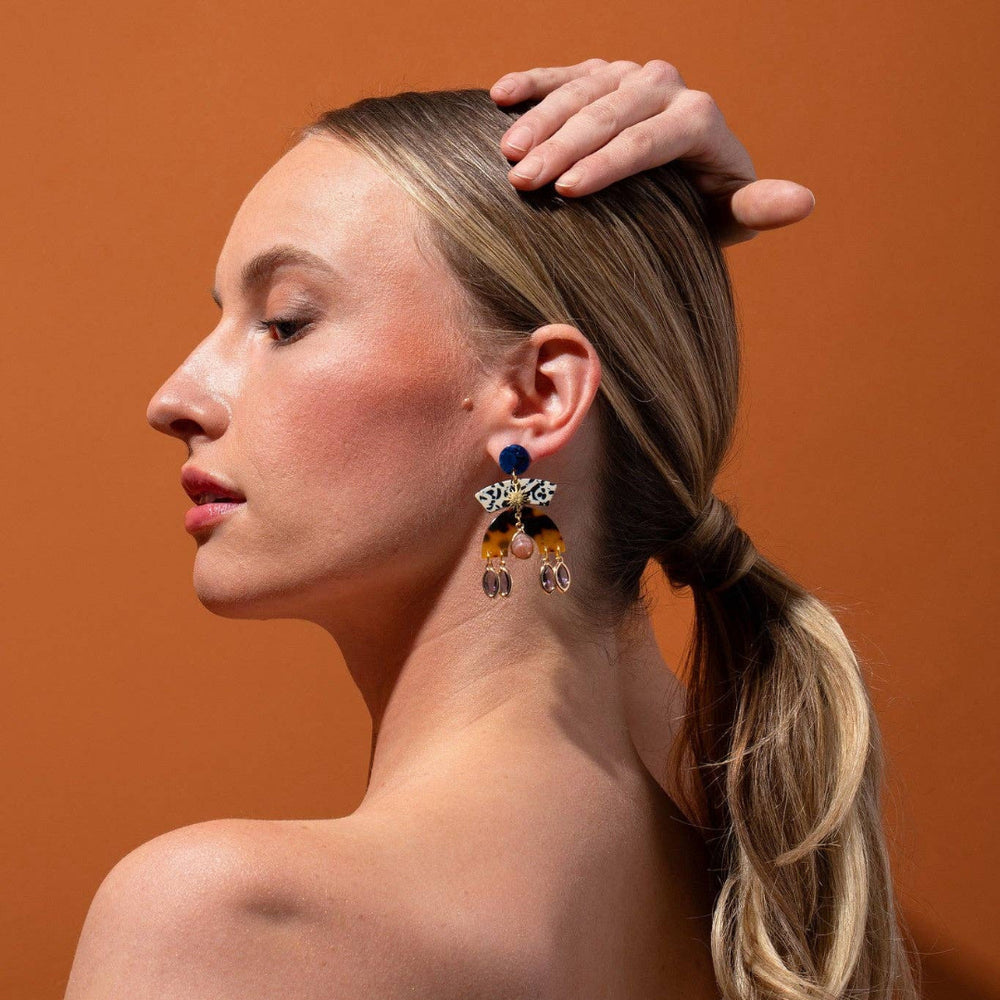 Woman wearing colorful earrings against an orange background