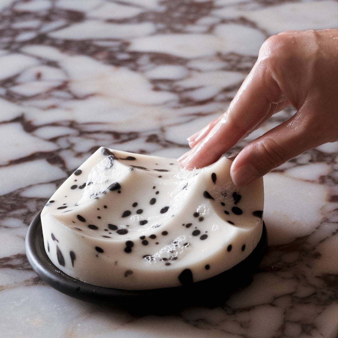 Hand touching a creamy dessert with chocolate chips on a marble surface