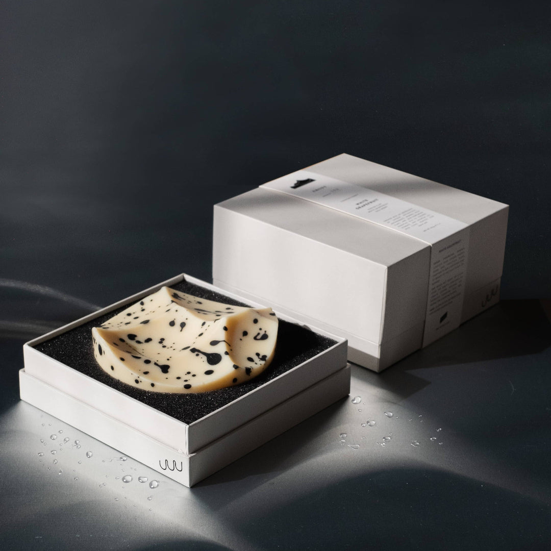 Cheese wheel in a black box with a white box on a dark background