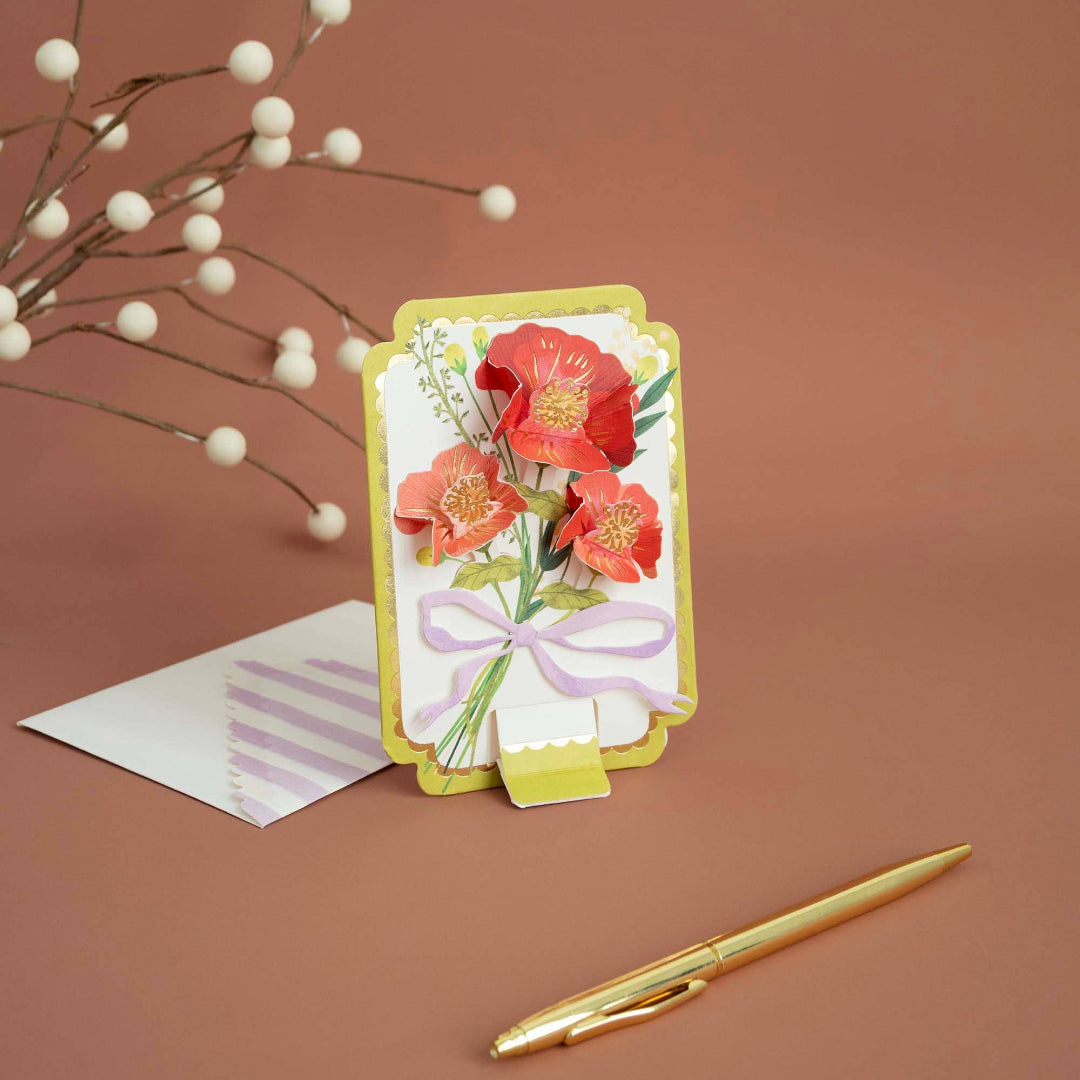 Greeting card with floral design on a brown background with a pen and envelope.