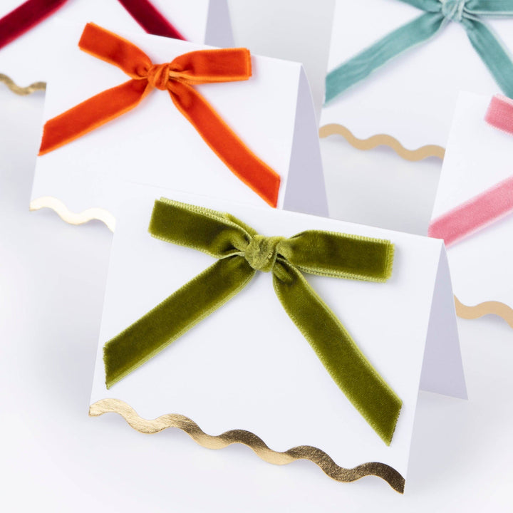 Colorful velvet bows on white paper with gold ribbons.