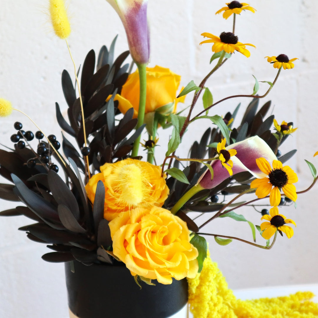 Vibrant | Close up on the bright florals in the arrangement. Accompanied by black leaves and berries.