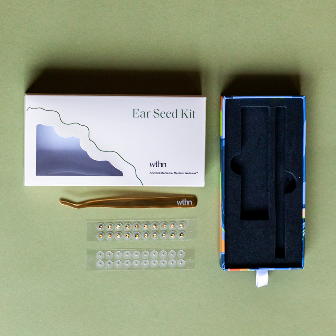 Ear seed kit with packaging, seeds, and tweezers on a green background