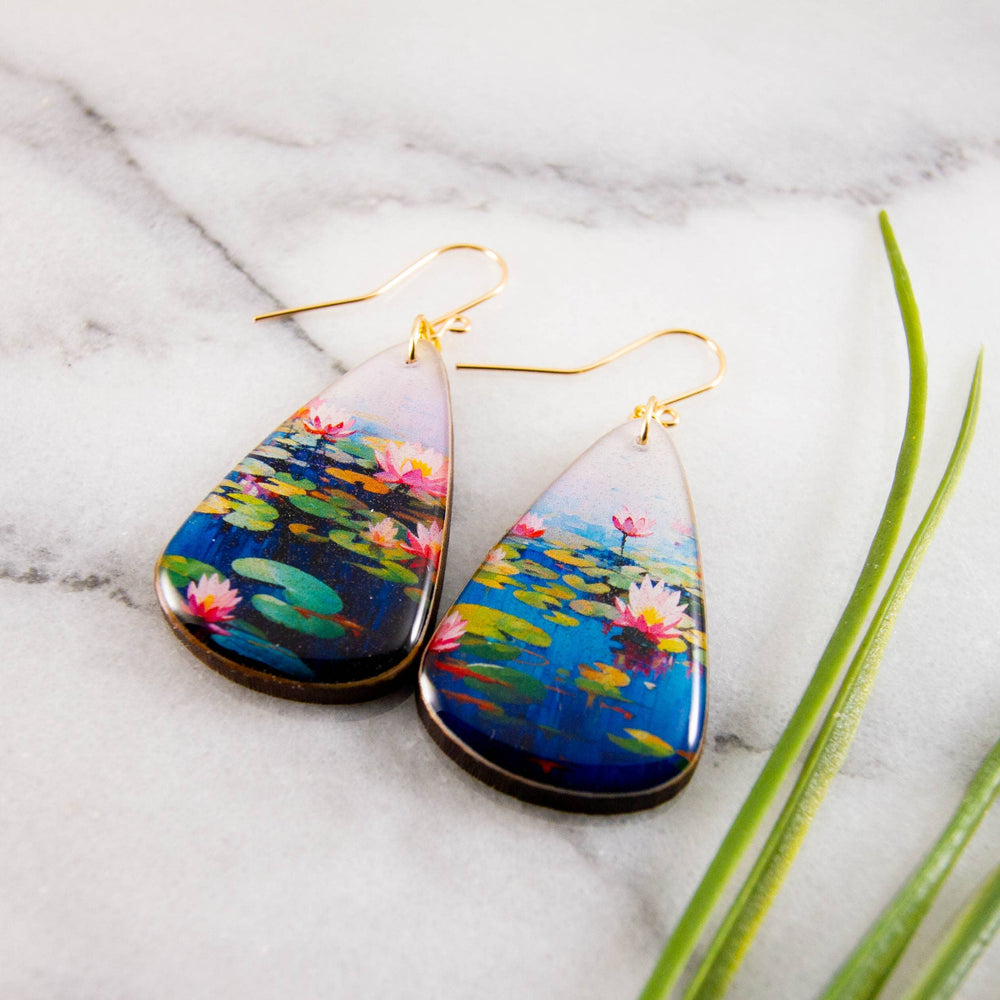 Teardrop-shaped earrings with waterlily design on a marble surface