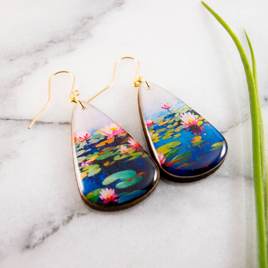 Teardrop-shaped earrings with waterlily design on a marble surface