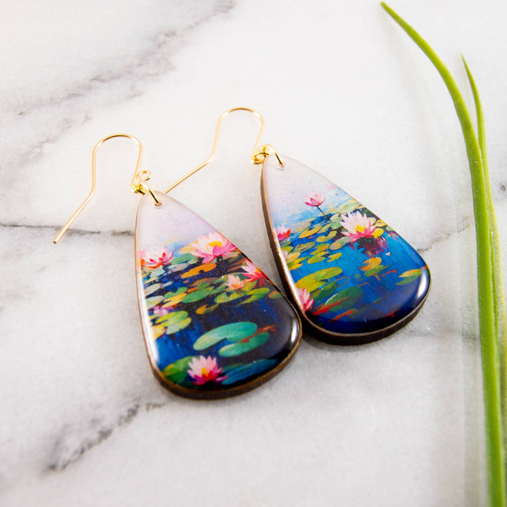 Teardrop-shaped earrings with waterlily design on a marble surface