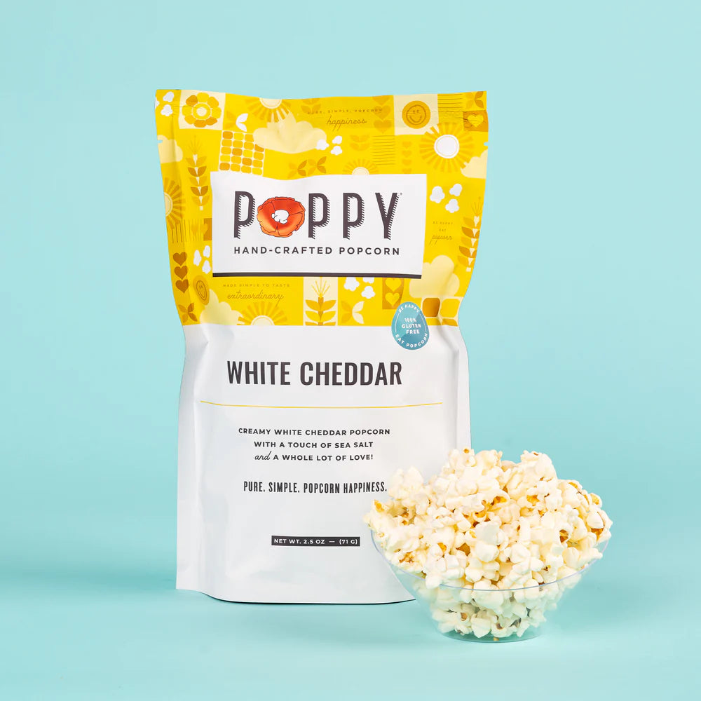 A bag of Poppy Hand-Crafted Popcorn with a touch of white cheddar, next to a bowl of popcorn.