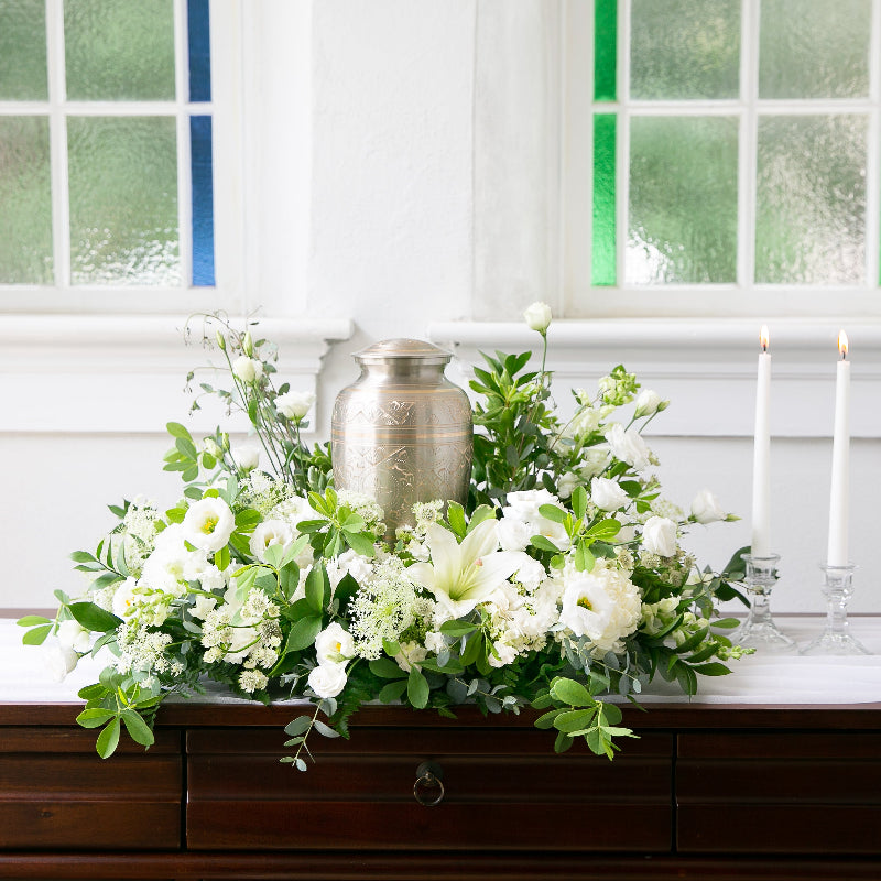 White sympathy urn arrangement with white blooms and greens