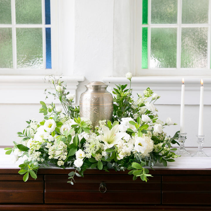 White sympathy urn arrangement with white blooms and greens