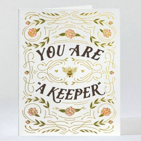 Love Keeper | Greeting Card | Elum Designs | A white card with gold detailing, pink flowers, greens, and a bee in the center. Text reads "You Are A Keeper".