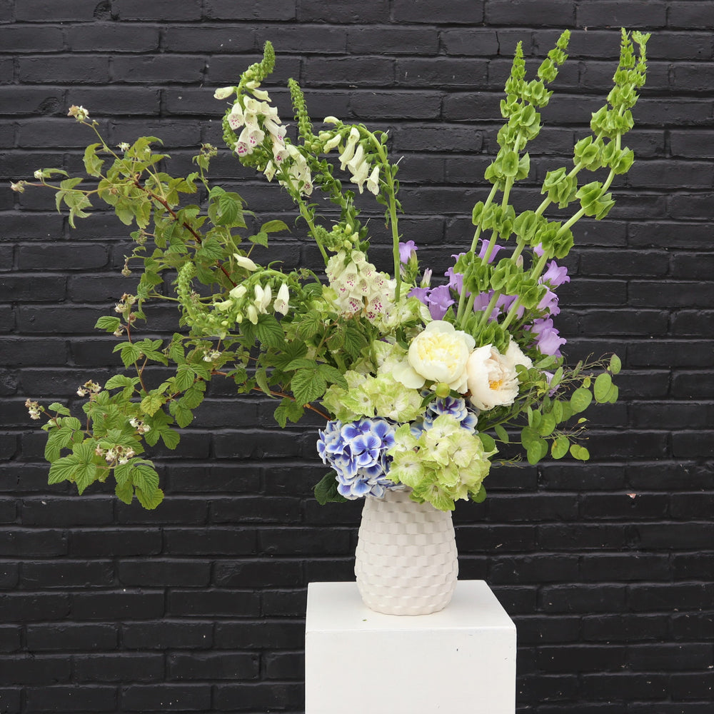 Dreamer | Photo of the summer arrangement in a white vase against a black brick background.