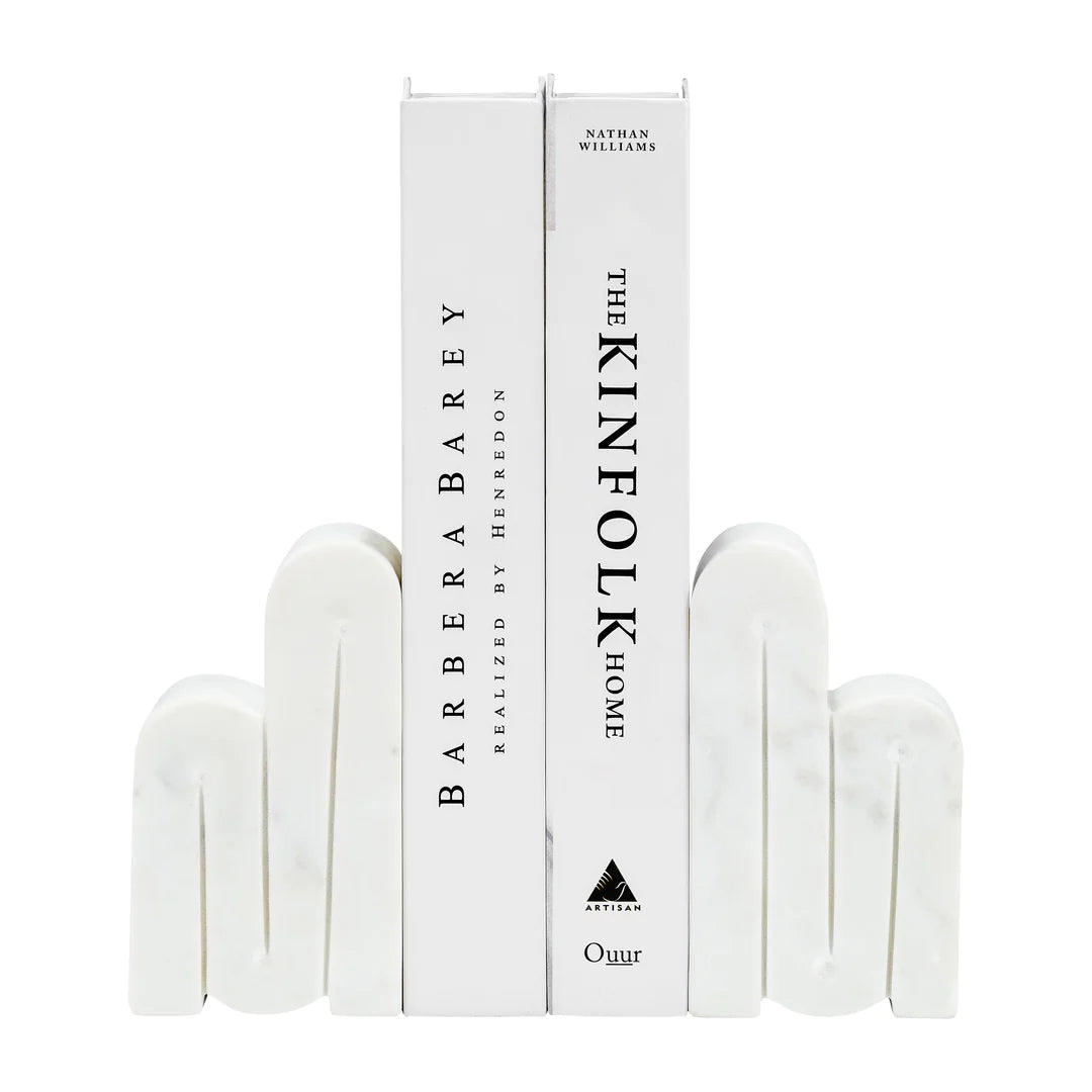 Swirly Marble Bookends | White marble bookends in a swirling pattern, holding up two books: BarberaBarey Realized by Henredon, and The Kinfolk Home by Nathan Williams".