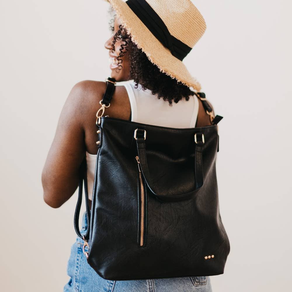 A black tote bag, backpack, purse, crossbody bag, with a side zipper.