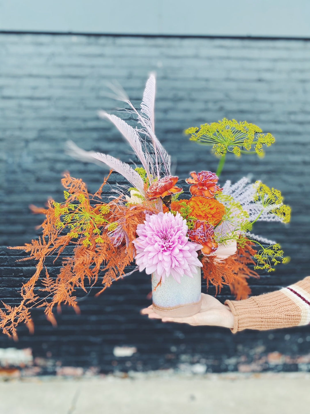 orange and lavender centerpiece photographed in front of a black brick wall