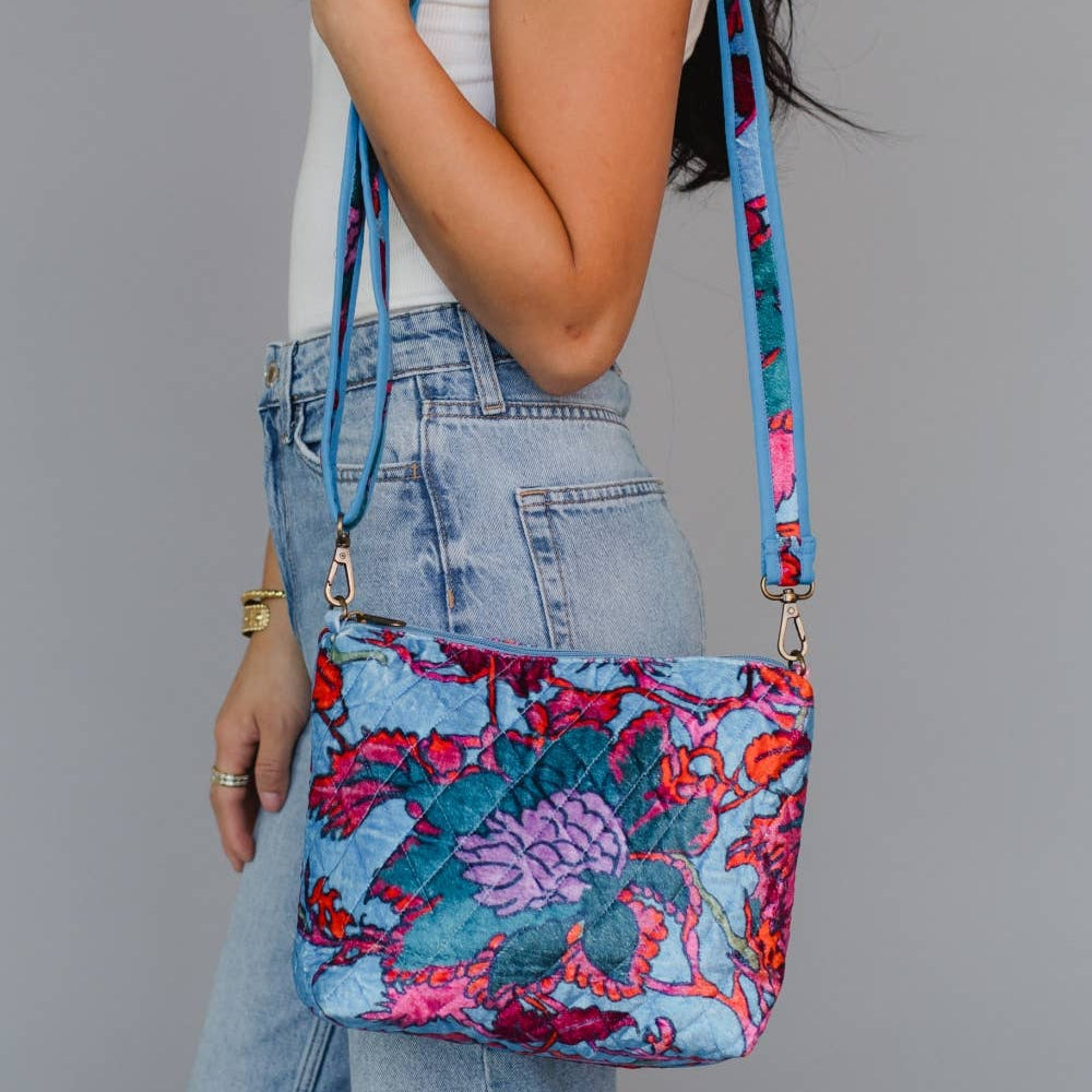 Woman holding a colorful floral-patterned handbag against a gray background