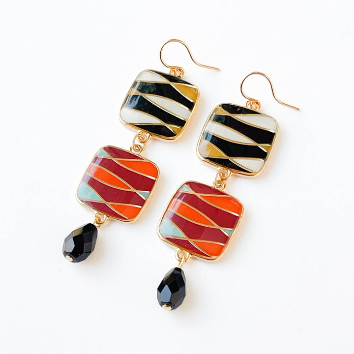 Nest Pretty Things | Long Statement Retro Dangle Earrings | Close up on the black, yellow, white, pink, orange, and blue earrings with gold accents.