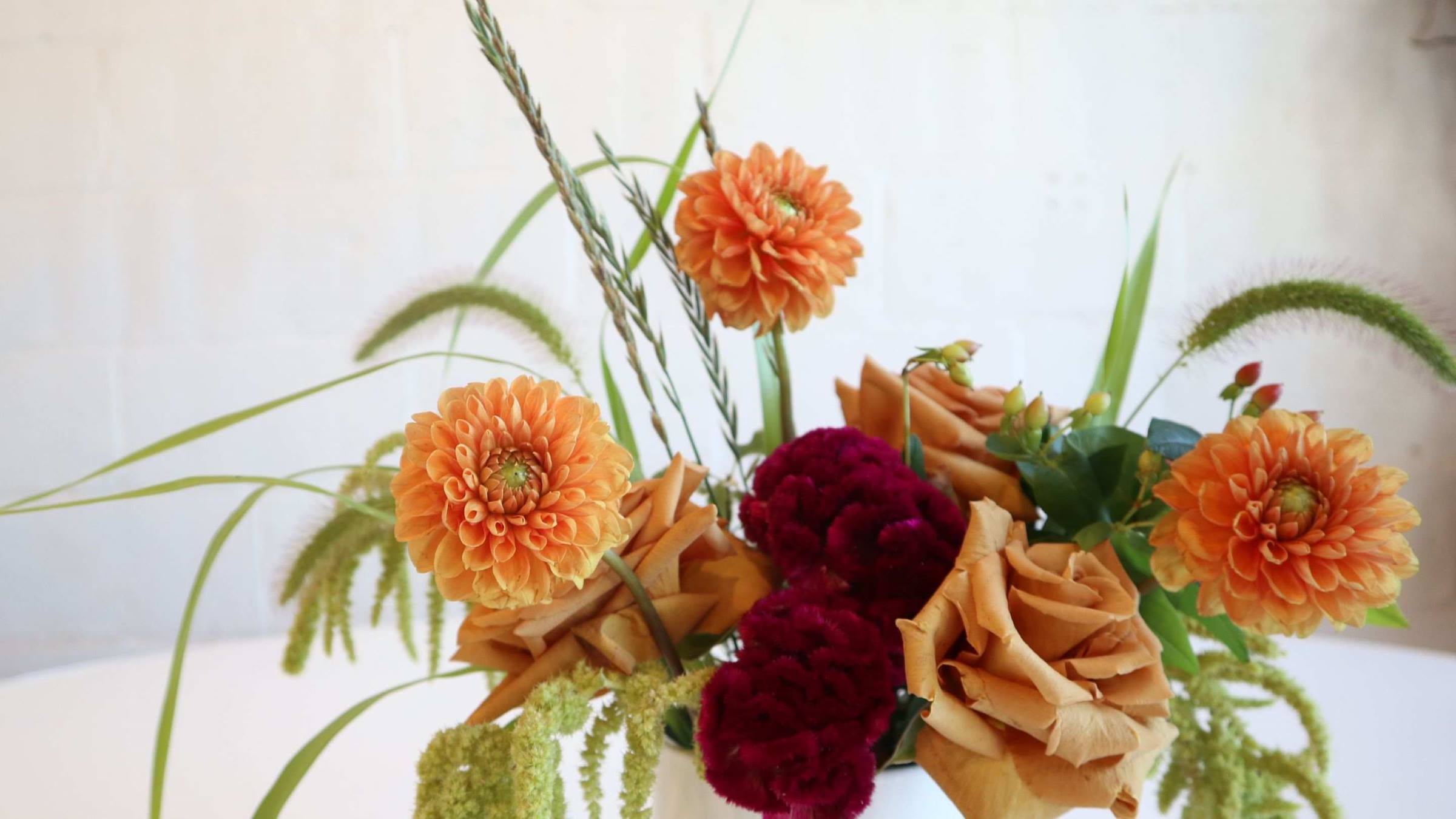 Vased Flower arrangement with dahlias, celosia, roses, and grasses.