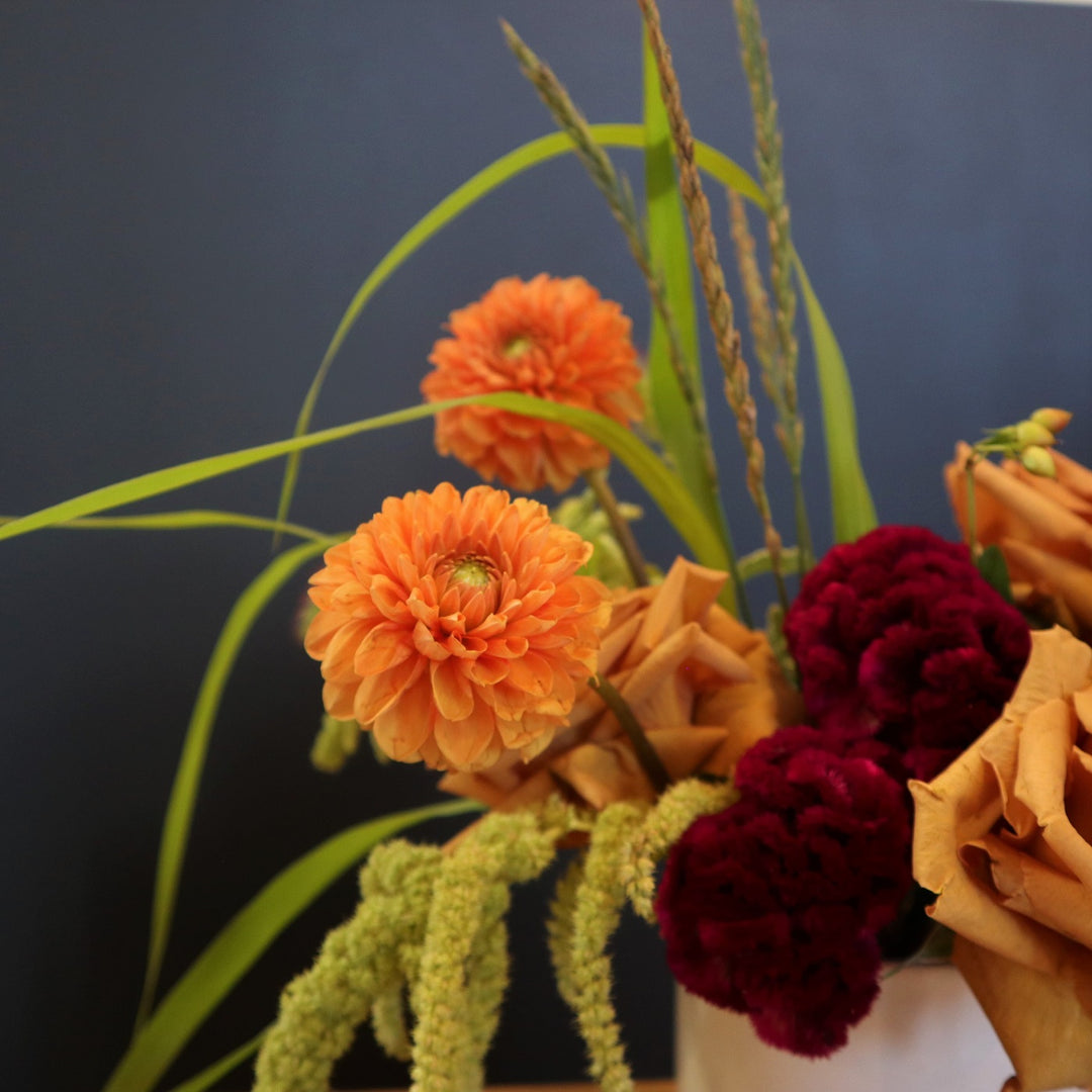 Golden | Stacy K Floral | Close up on the orange dahlias. Photo taken against a dark background.