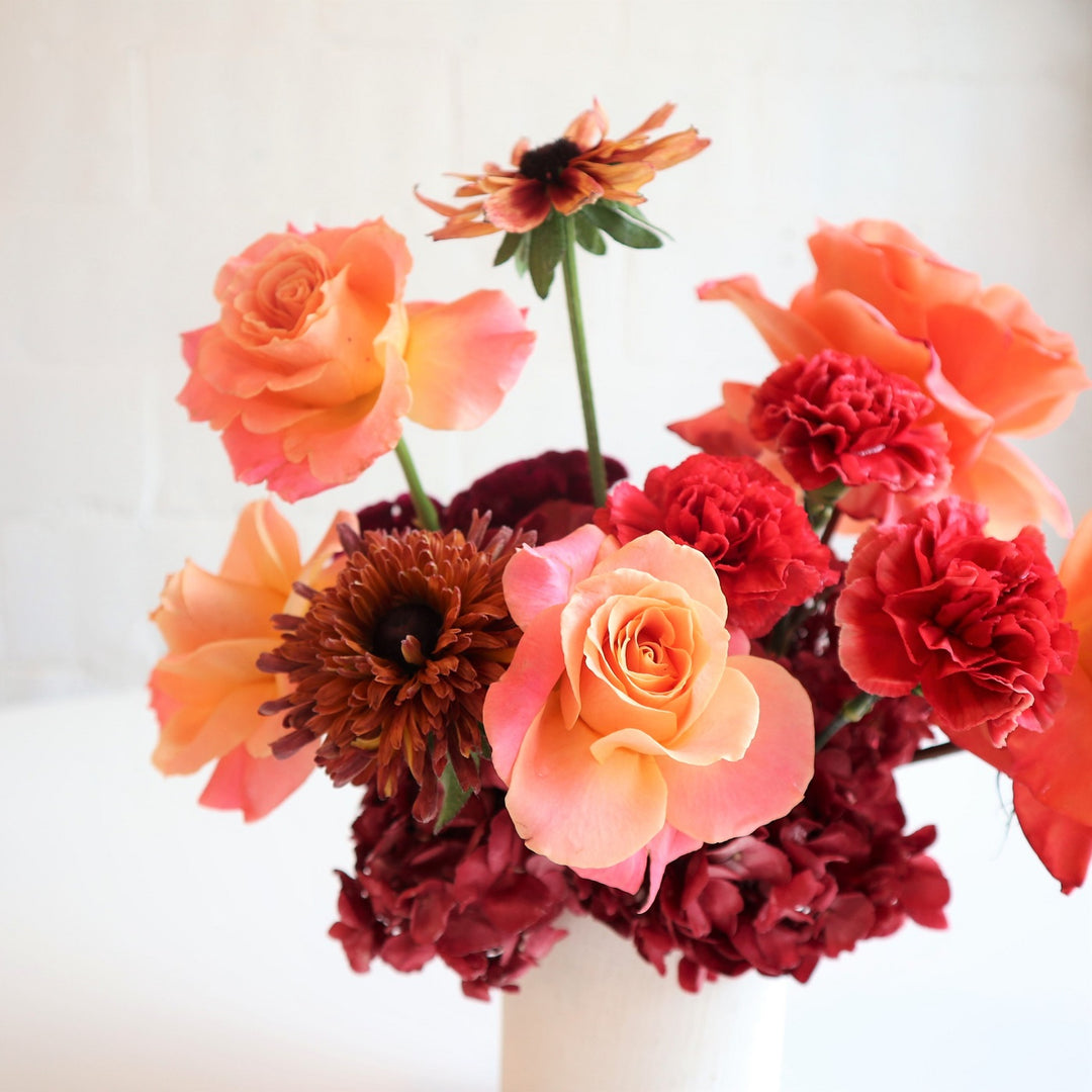 Abundance | A close up on the roses and mums. A beautiful arrangement with reds, oranges, and peach.