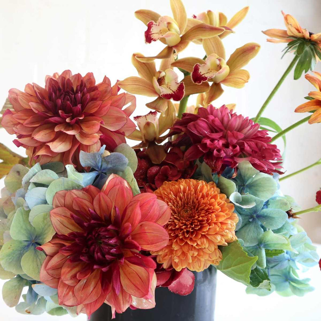 Fall collection floral arrangement of hydrangea dahlias, mums, orchids and more in rust orange mustard and  blue