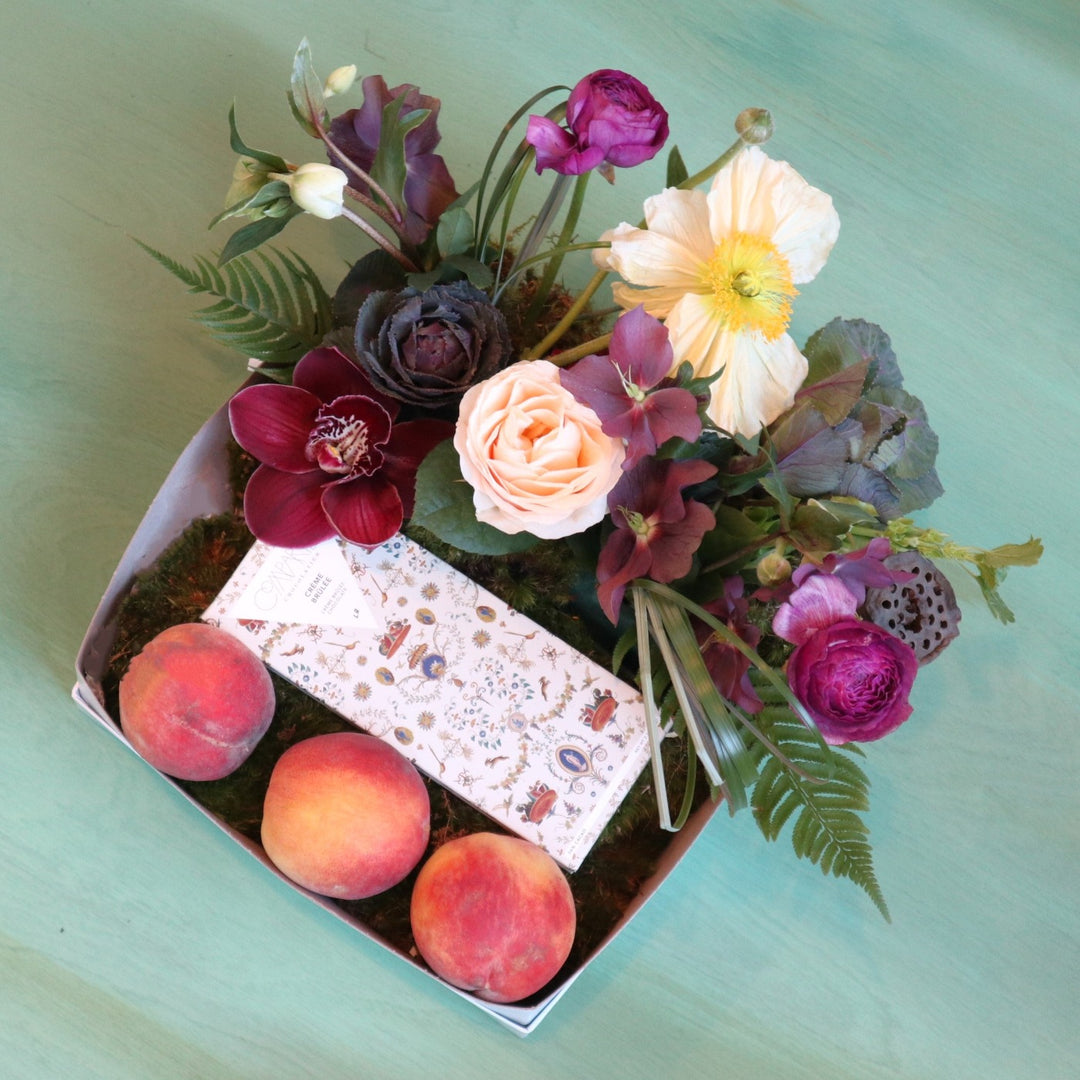 Fruit box with three peaches, Compartes chocolate and a floral arrangement with helleborus, poppies, kale, orchids, ranunculus.