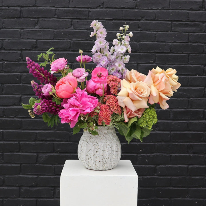 Magnificent | A photo of the arrangement against a black brick background.