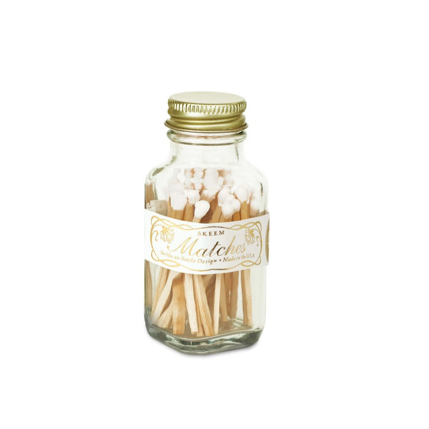Apothecary Match Bottle | A square glass bottle with a gold lid, and white tipped matches. Simple white and gold label. Text reads " Skeem, Matches, Made in the USA".