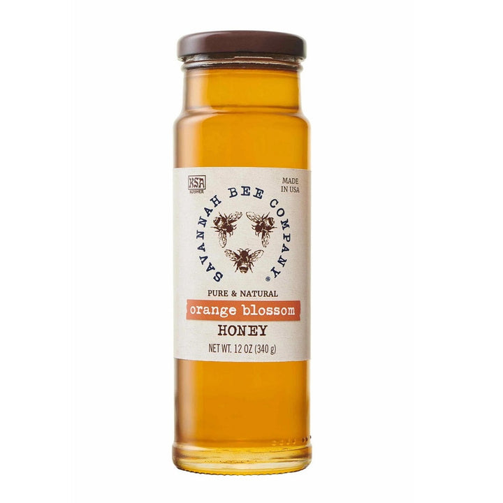 Savannah Bee 12 oz Honey Jar | Orange Blossom | A tall glass container with a simple label, decorated with the SBC logo. 12 oz.