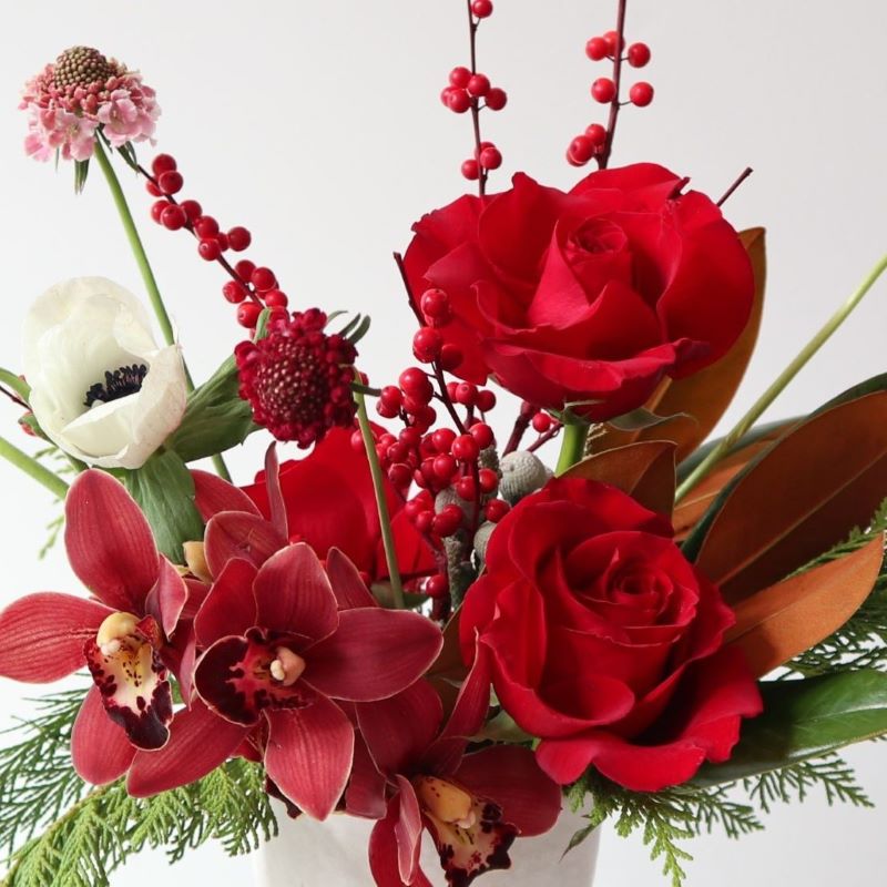 red holiday image with orchids roses and winter greens