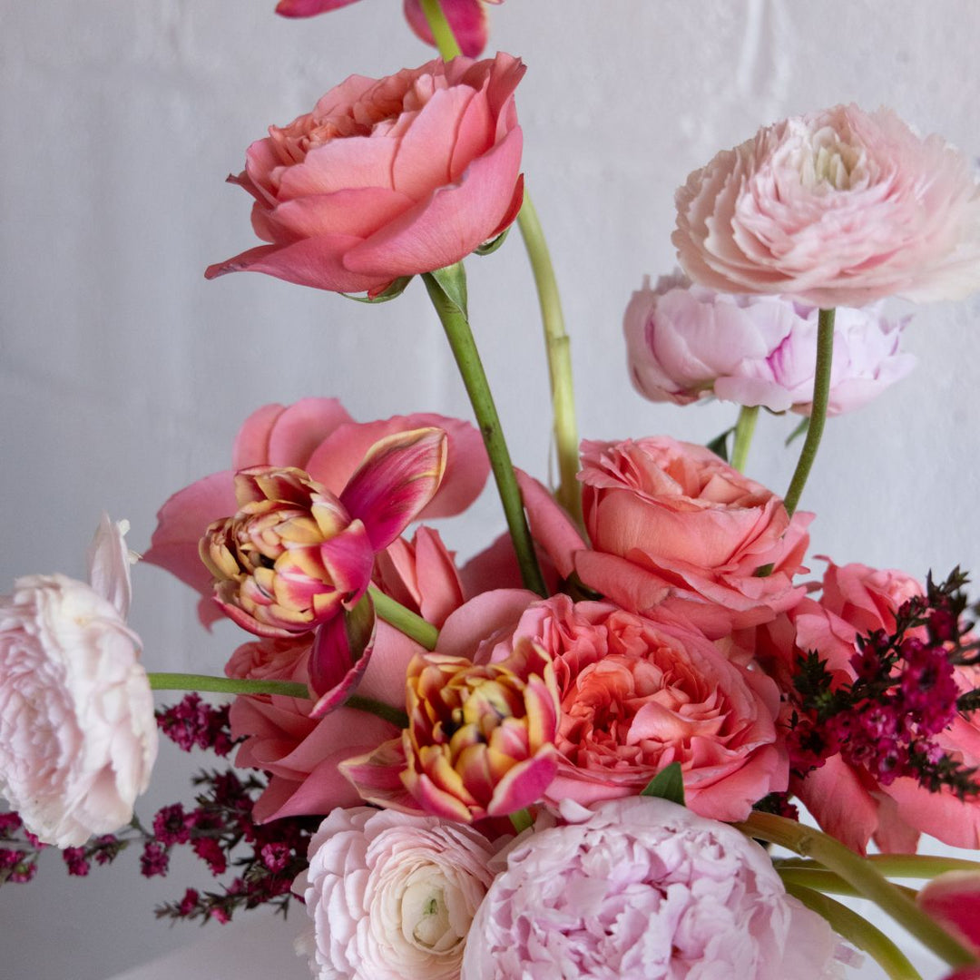 vase of pink flowers against a light gray background