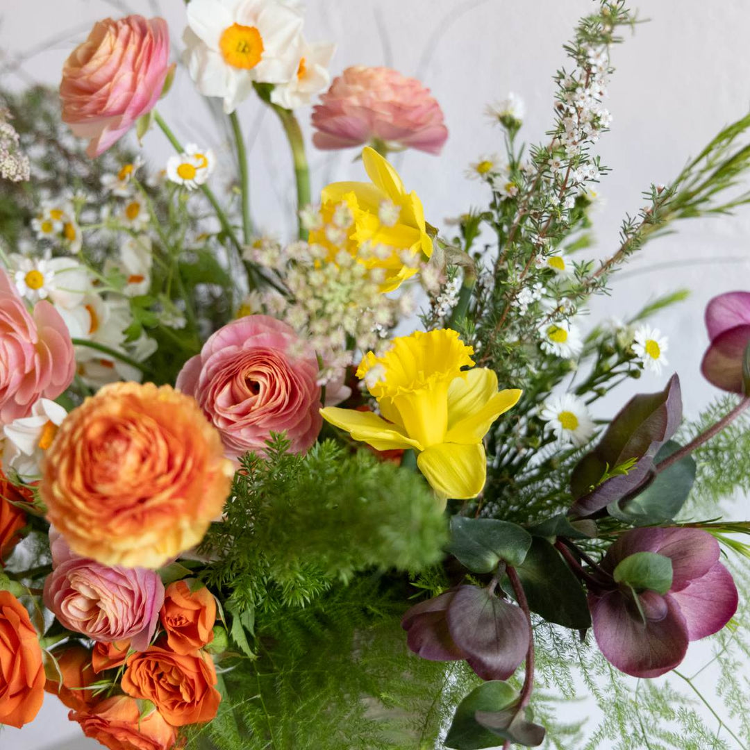 Bouquet of colorful flowers including roses and daffodils with a light background