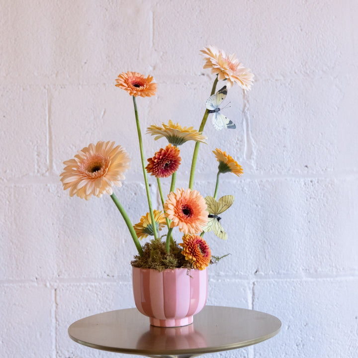 Pink vase with colorful flowers and butterflies