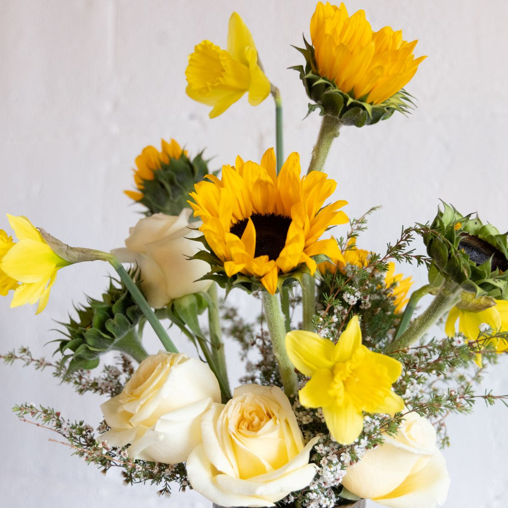 Bouquet of yellow sunflowers and white roses on a light gray background