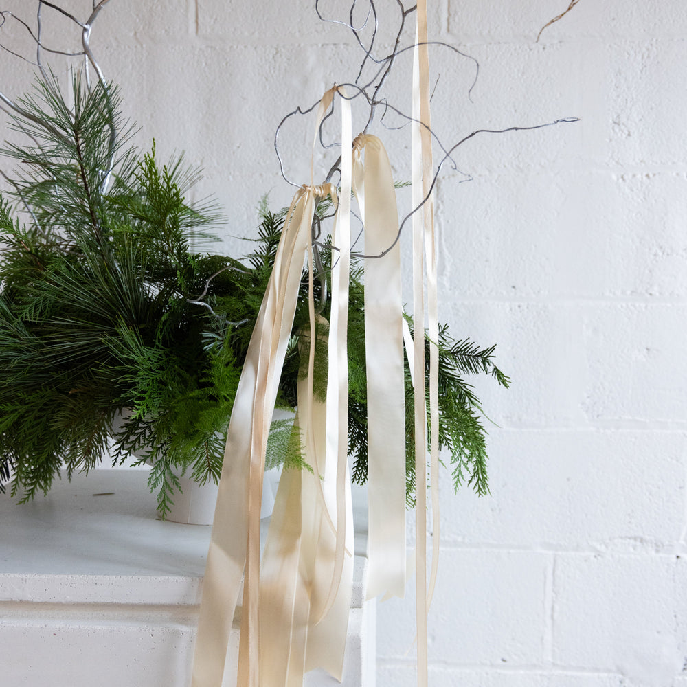 Decorative ribbons hanging from a branch with a white brick wall background