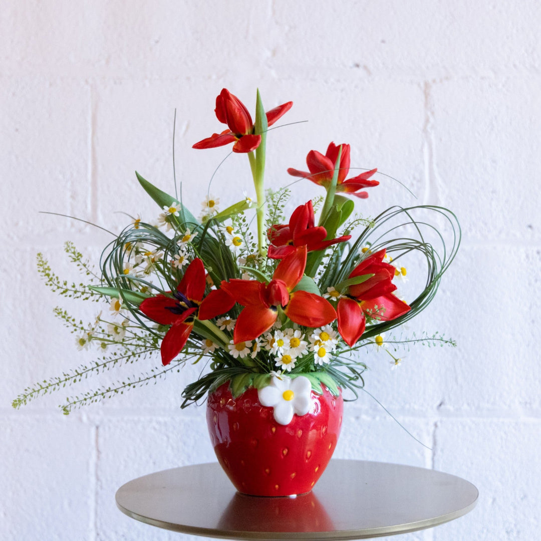 Red floral arrangement in a strawberry-shaped vase