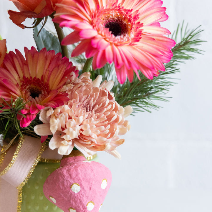 Bouquet of pink and peach flowers with green leaves on a light blue background