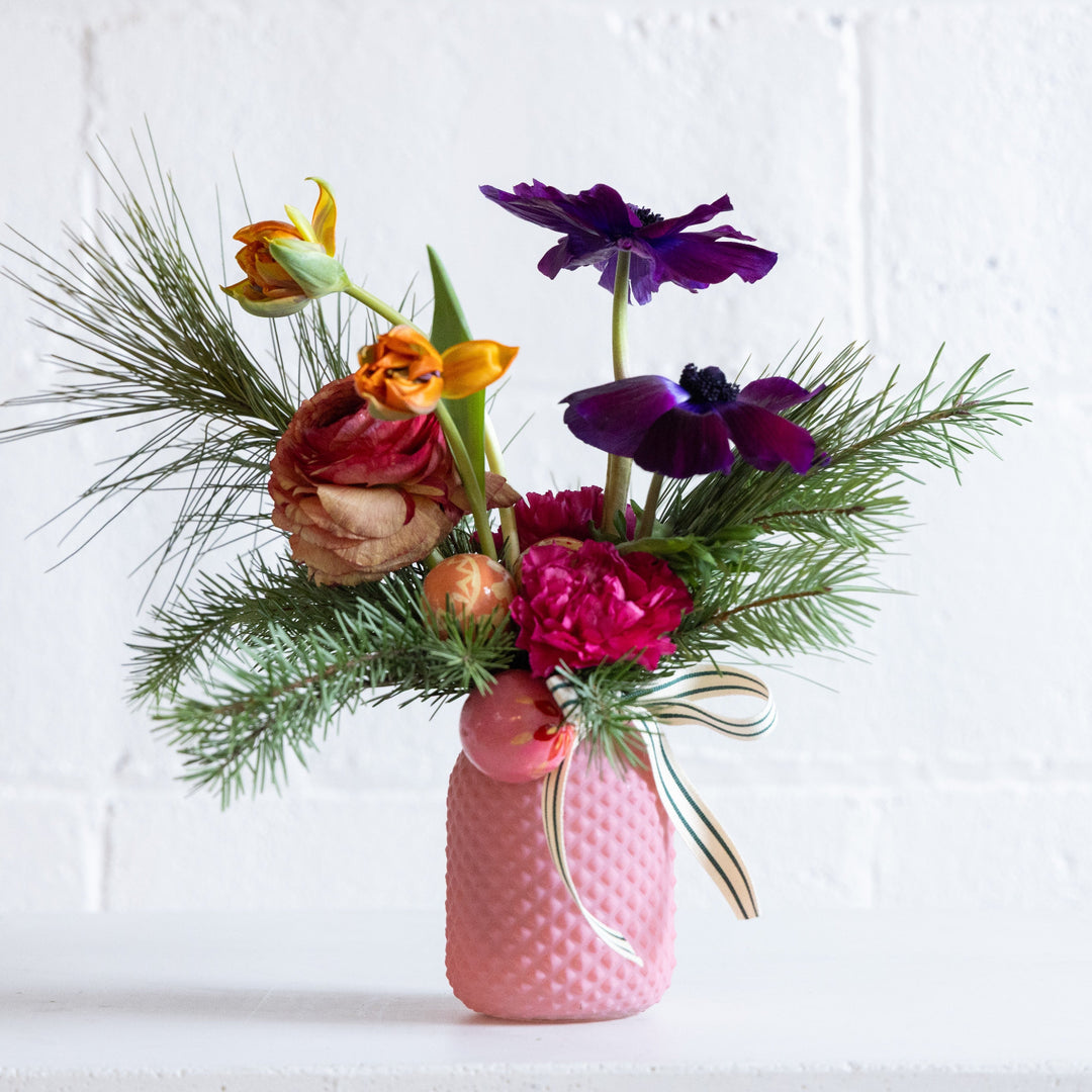 Colorful flower arrangement in a pink vase on a white background