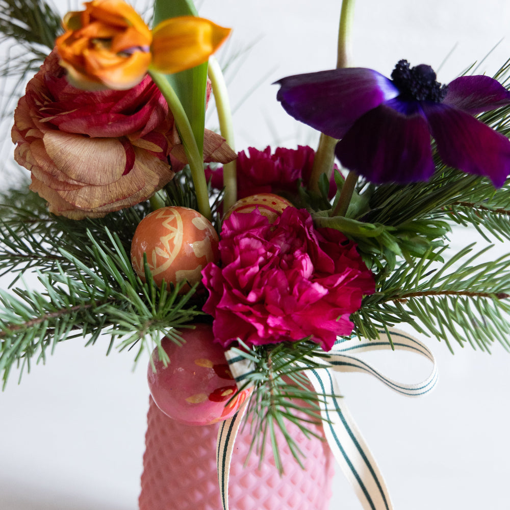 Colorful flower arrangement in a pink vase with a white background