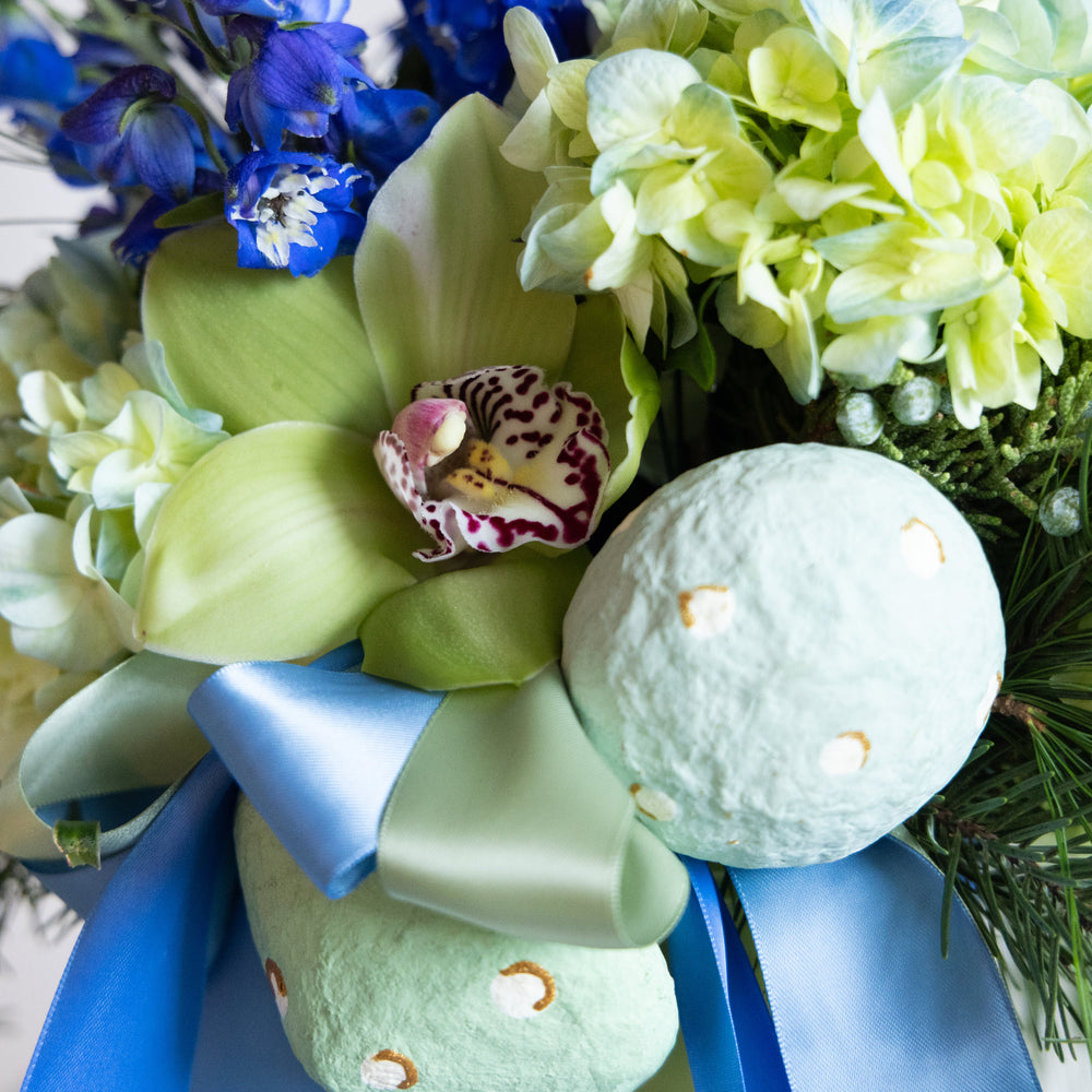 Bath bombs with a blue bow and green orchids on a white background