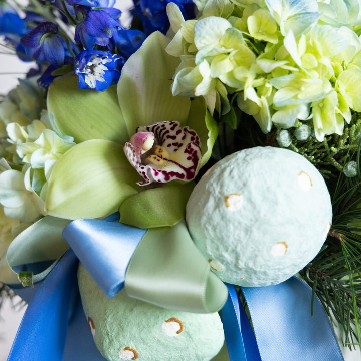 Bath bombs with a blue bow and green orchids on a white background