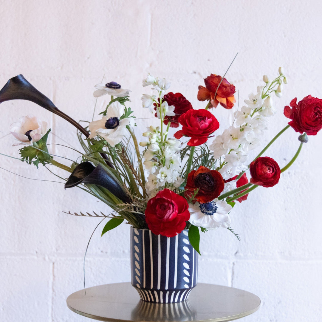 Bouquet of red, white, and green flowers in a striped vase