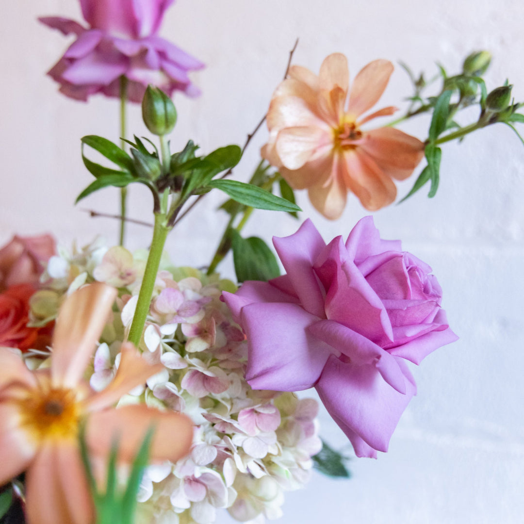 Colorful bouquet of flowers including pink, orange, and yellow flowers on a light background